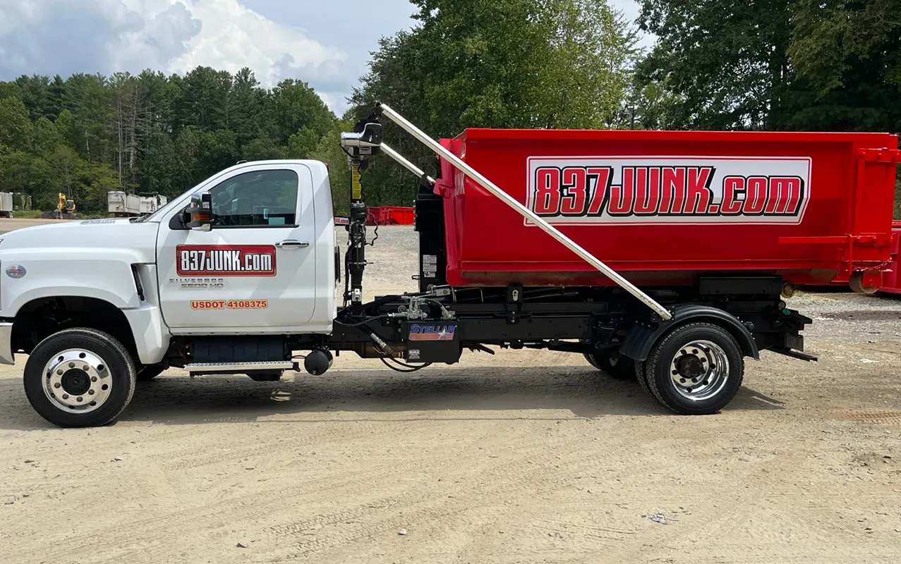 837JUNK truck transporting a roll-off dumpster