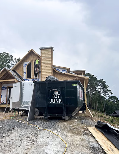 roll off dumpster rental sitting outside on a home construction jobsite holding trash and waste